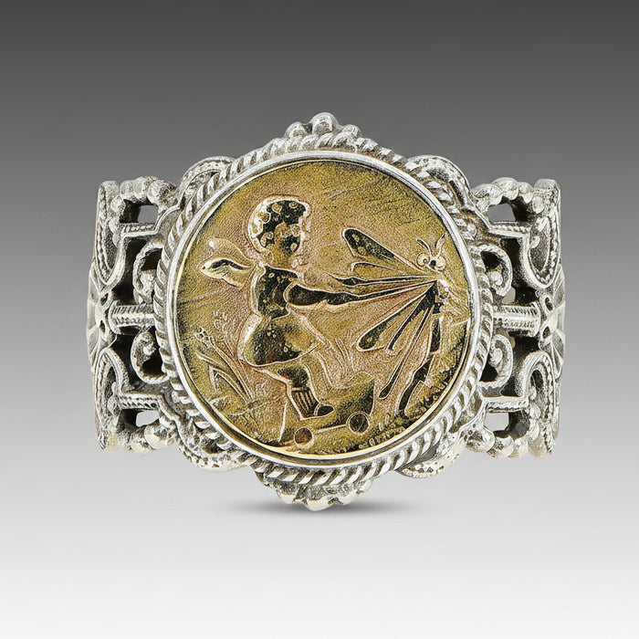 A silver ring featuring a hand-carved cherub design in a circular pattern, set against a gray background.