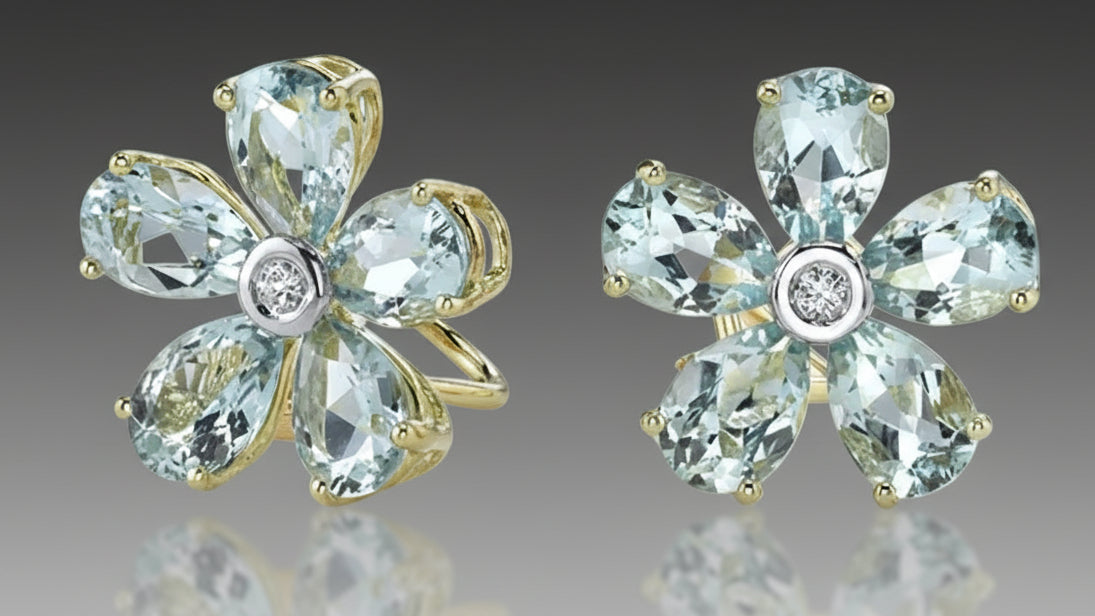 Flower-shaped earrings with blue gemstones and gold accents on a gray background