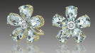 Flower-shaped earrings with blue gemstones and gold accents on a gray background