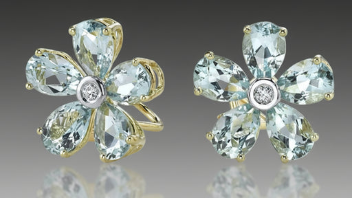 Flower-shaped earrings with blue gemstones and gold accents on a gray background