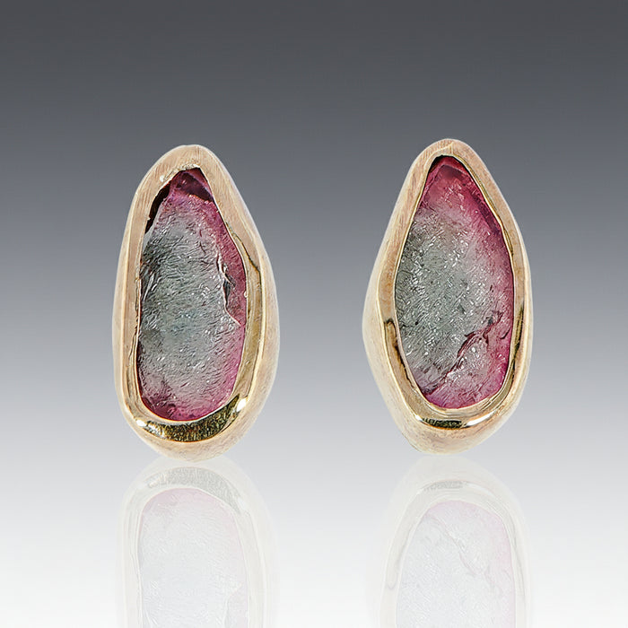 A pair of bi-color tourmaline stud earrings set in 18k yellow gold with sterling silver posts.