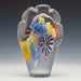 A multicolored flattened paperweight with a cloud shape made by Hunting Studio Glassworks.