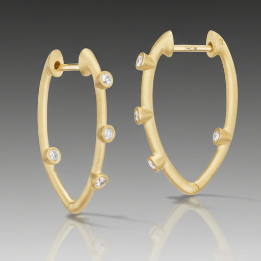 A pair of 18k gold hoop earrings with brilliant cut diamonds set within the hoops.