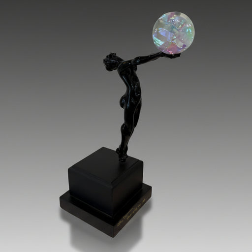 Black statue holding a colorful sphere on a black platform