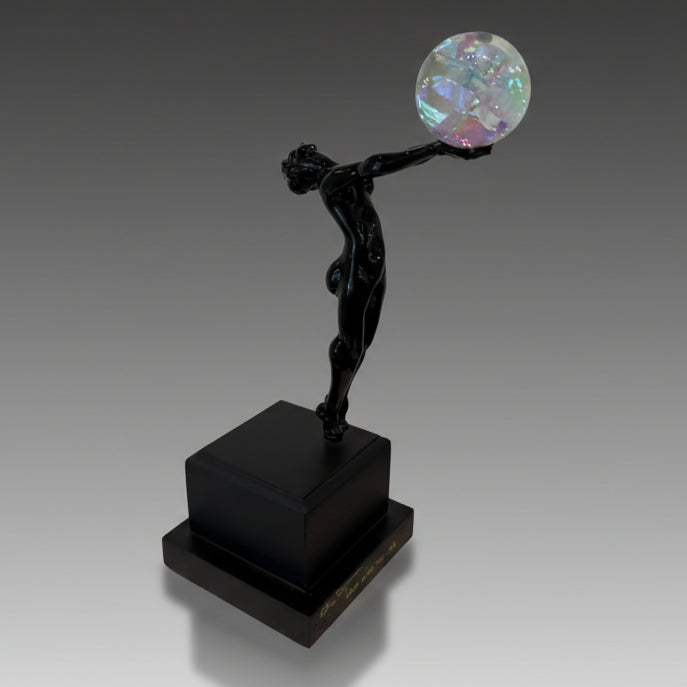 Black statue holding a colorful sphere on a black platform