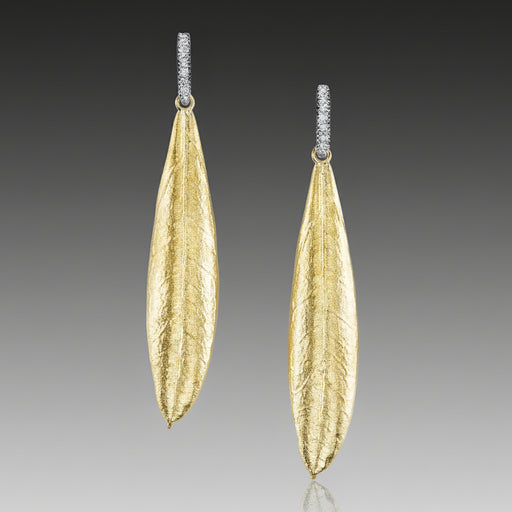 Gold leaf-shaped earrings on a gray background