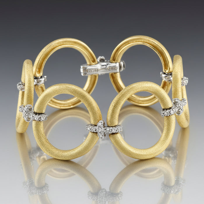 Gold bracelet with interlocking rings and diamond accents on a gray background