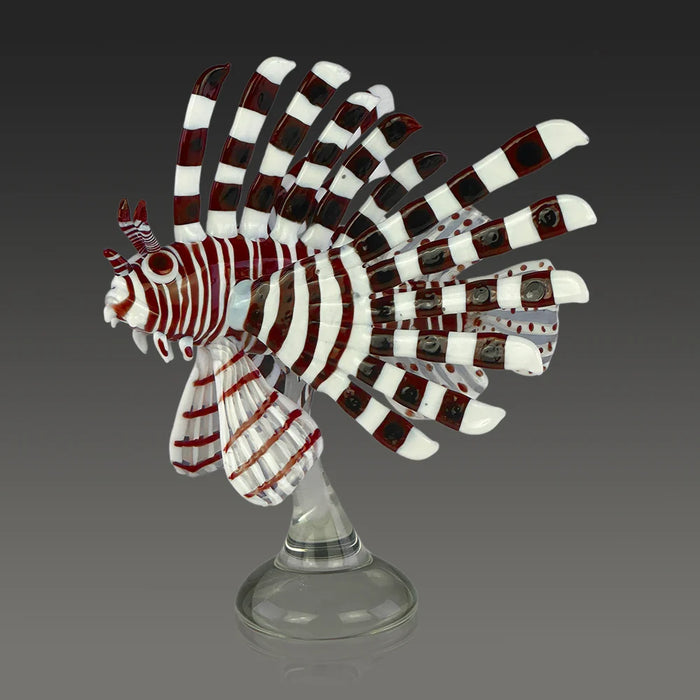 Decorative glass fish sculpture with red and white stripes on a gray background