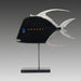 A mixed media sculpture of a fish with a predominantly black body, featuring a yellow dot stripe, silver fins, and a blue eye detail, displayed on a metal stand.