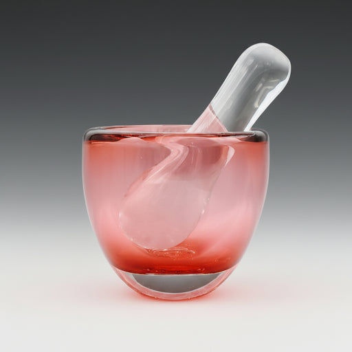 A pink blown glass mortar with a clear glass pestle.