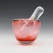 A pink blown glass mortar with a clear glass pestle.