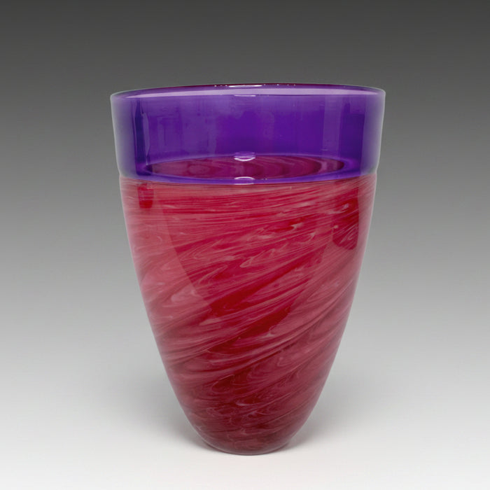 A blown glass vase with a pink and purple swirled pattern and an incalmo rim.