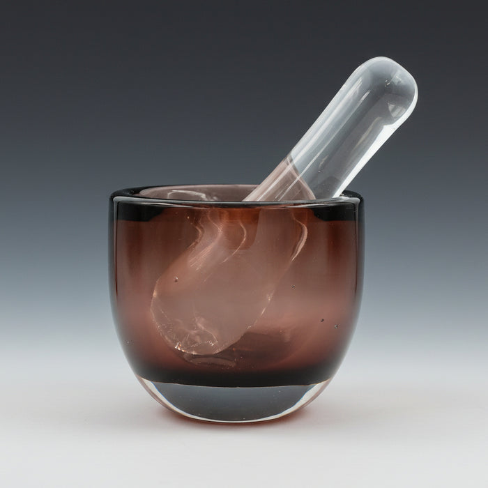 A plum colored mortar with a clear glass pestle.