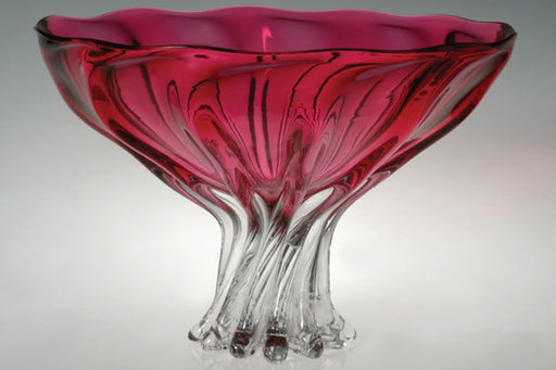 Glass bowl with red interior and clear base on a gray background