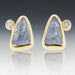 A pair of 18k yellow gold stud earrings with Tanzanite and small diamond accents.