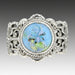 A sky blue Leo Popper glass button ring set in sterling silver with intricate filigree work, displayed against a white background.
