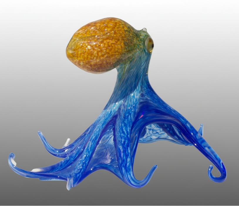 Glass octopus with blue tentacles and an orange head on a gray background