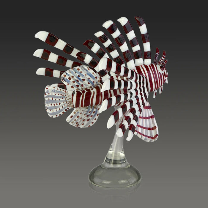 Glass sculpture of a lionfish on a stand against a dark background