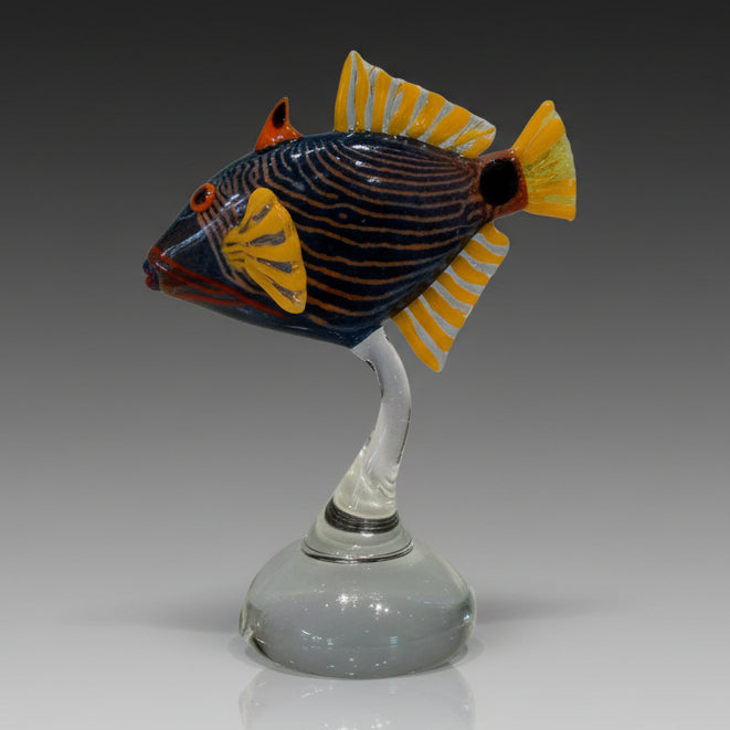 Decorative glass fish sculpture on a white pedestal against a white background