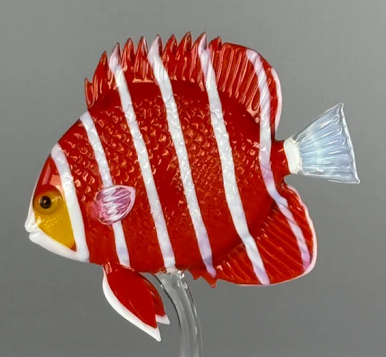 Glass fish sculpture with red and white stripes on a gray background