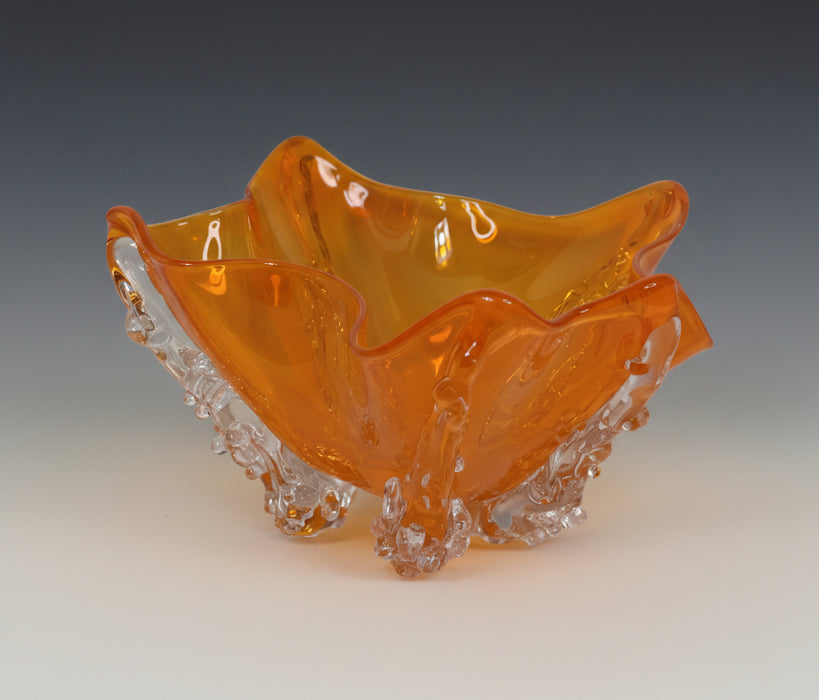 Orange glass bowl with textured base on a light gray background