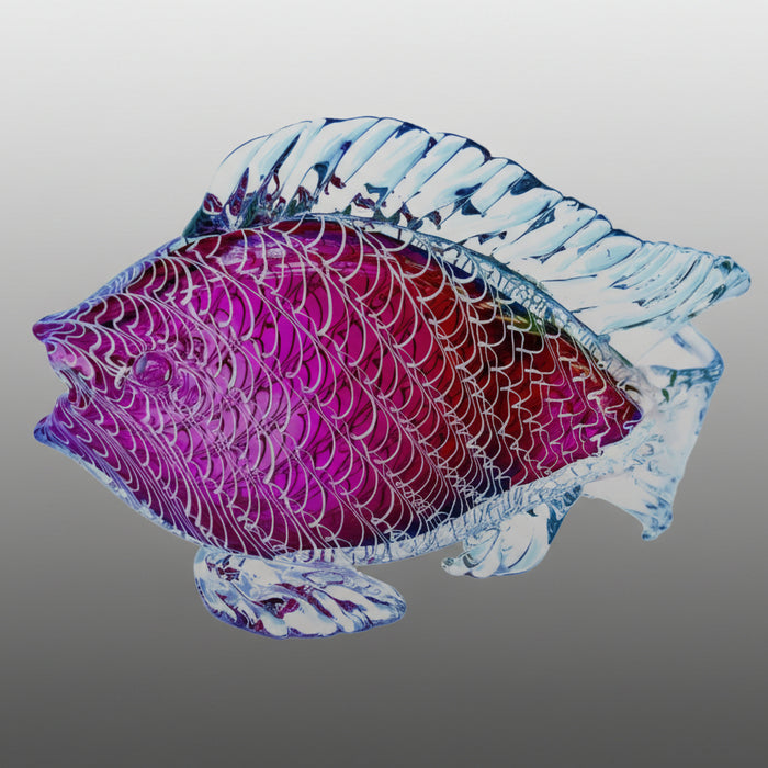 Glass sculpture of a fish with purple and blue patterns on a gray background