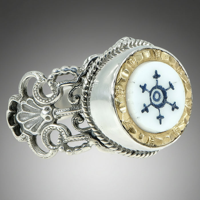 A Victorian Nautical Glass Button Ring with a white and blue glass center, surrounded by a metallic border with intricate detailing, set in a sterling silver band.