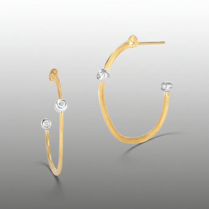 Gold hoop earrings with diamond-like stones on a gray background