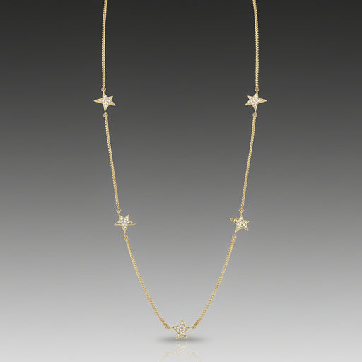 A Graffiti 5 Star Constellation Station Necklace with multiple star-shaped diamond stations set in a row yellow gold and diamonds with gray background