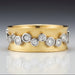 An 18k yellow and white gold ring with multiple diamond clusters set throughout the band.