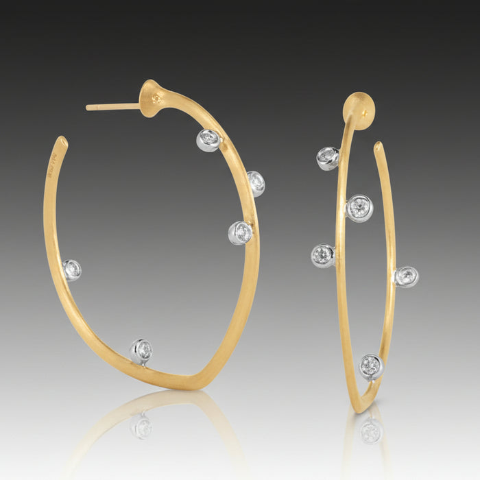 A pair of 18k white and yellow gold hoop earrings, adorned with diamonds.