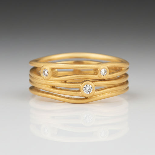 A handcrafted 18k brushed yellow gold ring with round, brilliant cut diamonds.