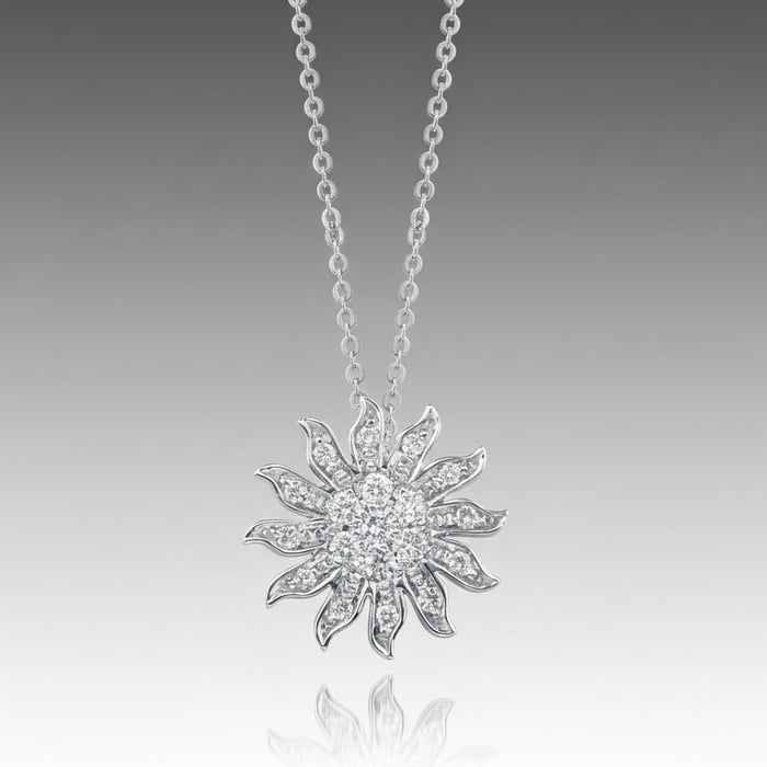 A silver pendant necklace with a graffiti sun icon design, featuring a round, brilliant cut diamond in a pave setting.