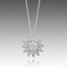 A silver pendant necklace with a graffiti sun icon design, featuring a round, brilliant cut diamond in a pave setting.