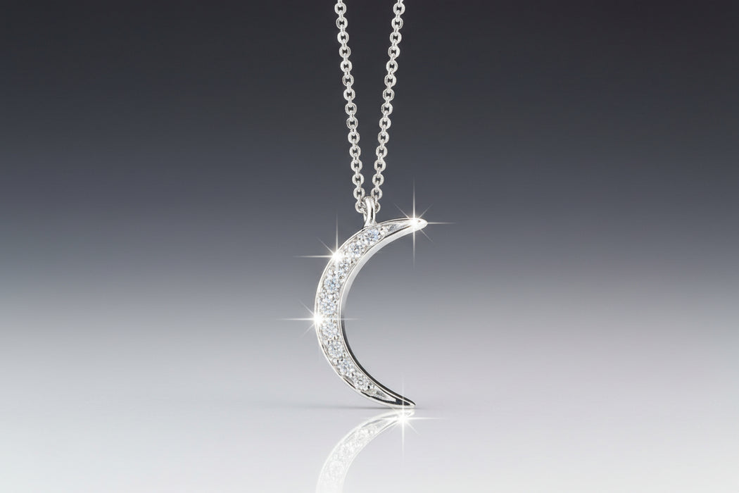 A crescent moon-shaped necklace with a central round brilliant cut diamond in a pave setting, suspended from an adjustable chain.