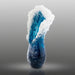 Blue glass sculpture with white crystalline structure on a gray background