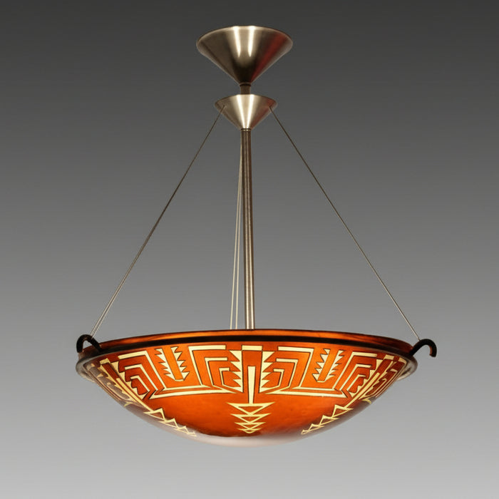 A glass chandelier with intricate geometric carving, featuring a mix of amber and tan colors, suspended by metal fittings against a neutral background.