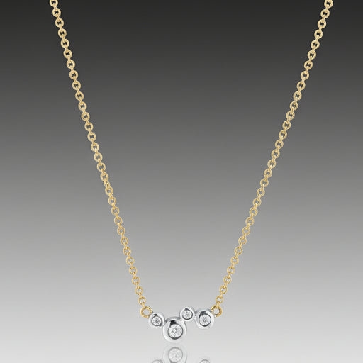 A Scribble Single Cluster Necklace with an 18k yellow gold chain and 18k white gold bezels with round, brilliant cut diamonds.
