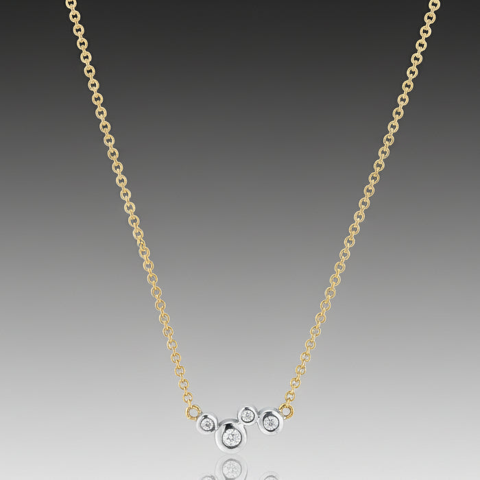 A Scribble Single Cluster Necklace with an 18k yellow gold chain and 18k white gold bezels with round, brilliant cut diamonds.