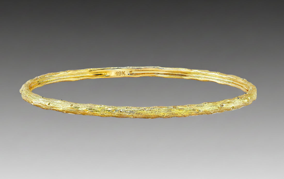 A textured gold bracelet with a solid pattern, likely made from 19k yellow gold, as part of Aaron Henry's Signature Arbor Collection.